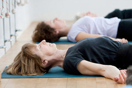 Iyengar yoga students lying on the floor pracrising pranayama breathing exercises